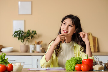 Thoughtful young woman writing recipe in book at home