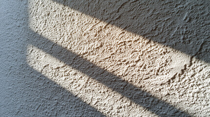 Fototapeta premium Close up detailed texture of rough beige wall surface with natural light and shadows creating warm and rustic background
