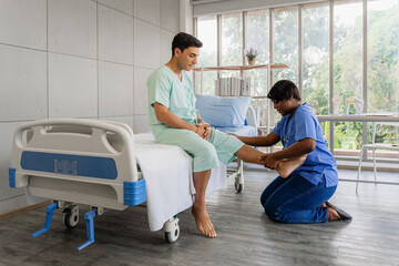 Female physiotherapist examining a male patient's leg and knee injury, providing hands-on...