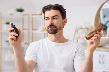Man with comb and serum for hair growth at home