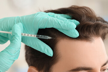Doctor giving man injection for hair growth in clinic, closeup
