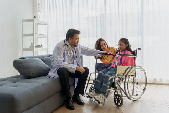 Caring doctor making a house call to encourage a young disabled girl in a wheelchair, with her mother's support. Home healthcare specialist showing test results on a tablet to a child - Powered by Adobe