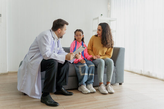 Doctor explaining test results on a digital tablet to a mother and daughter during a home visit. Friendly pediatrician giving a high five to a young patient, signifying good news and building trust.