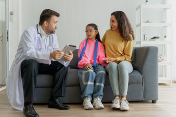 Doctor discussing test results with a mother and daughter using a digital tablet in a modern...
