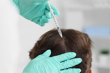 Doctor giving man injection for hair growth in clinic, closeup