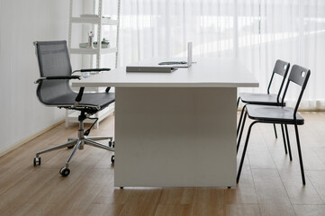 Modern and minimalist empty doctor's office or consultation room with a white desk and chairs. Clean and professional workspace interior, suitable for a clinic, office, or job interview setting.