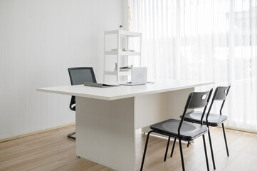 Modern and minimalist empty doctor's office or consultation room with a white desk and chairs. Clean and professional workspace interior, suitable for a clinic, office, or job interview setting.