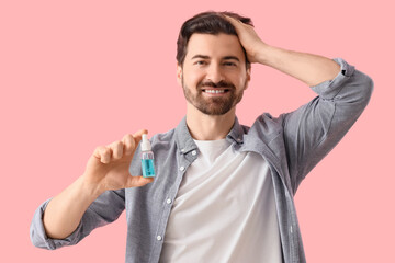 Man holding serum for hair growth on pink background