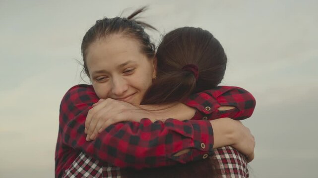 girl hugs her friend outdoors nature, happy family, daughter smiles on mom's shoulder, trust relationships of people, kindness and support with good smile emotions, sincere tenderness day of gratitude - Powered by Adobe