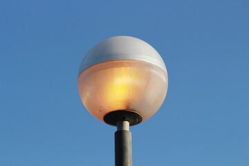 street lamp on blue sky. one night lamp post shines with a faint light on a blue background 