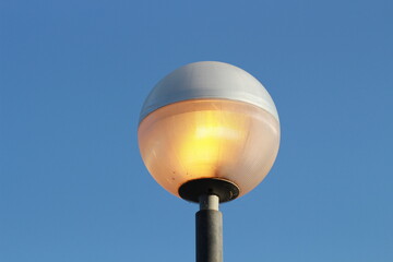 street lamp on blue sky. one night lamp post shines with a faint light on a blue background 