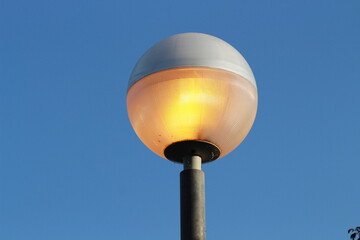 street lamp on blue sky. one night lamp post shines with a faint light on a blue background 