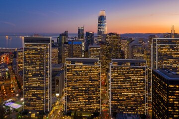 Obraz na płótnie Canvas Aerial view of the illuminated San Francisco skyline at dusk in California, USA. The buildings are lit up as people work late into the evening.