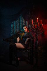 Beautiful vampire woman sitting on an ancient throne in an old crypt illuminated by candlelight...