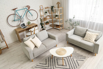 Interior of home office with workplace, bicycle and sofas