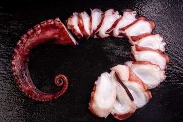 Closeup, Raw Tentacles of octopus on black plate , Sashimi kraken tentacles on black plate.