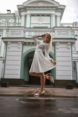Stunning girl in white dress posing in front of an old building background.