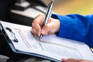 Action of a repairman is checking on multi-point checklist form during perform service the car...