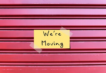 Business shop door closed with text written - We're moving -  means store is relocating to a new place. Leaving current to settle into a new location