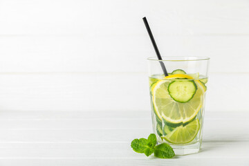 Cucumber water with lemon, lime and mint on a wooden table. Water infused with sliced...