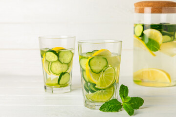 Cucumber water with lemon, lime and mint on a wooden table. Water infused with sliced...
