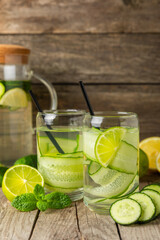 Cucumber water with lemon, lime and mint on a wooden table. Water infused with sliced...
