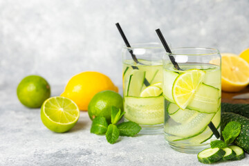 Cucumber water with lemon, lime and mint on a wooden table. Water infused with sliced...
