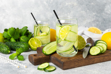 Cucumber water with lemon, lime and mint on a wooden table. Water infused with sliced...