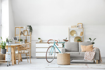 Interior of home office with workplace, bicycle and sofa