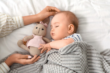 Female hands and little baby with toy bunny sleeping on bed, top view