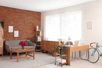 Interior of modern home office with workplace, bicycle and sofa