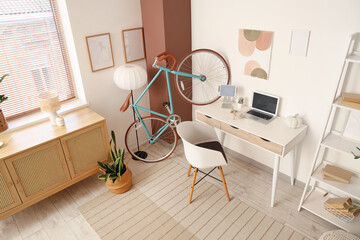 Interior of home office with workplace, bicycle and commode