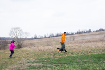 Walking through a calm countryside during early spring with a joyful dog and two people enjoying...