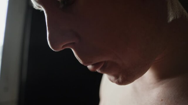 Close-up of boxer inserting black mouthguard while preparing for boxing practice in dimly lit training space