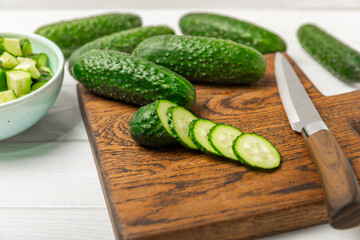 Cucumber on wooden background. Slice of cucumber on background. Fresh organic green cucumbers gherkin. Vegan. Salad ingredient. Farm vegetables. Cut vegetables with knife. Space for text. Copy space