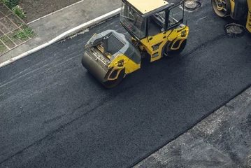 Workers lay a new asphalt coating using hot bitumen. Work of heavy machinery and paver. Top view © Artem