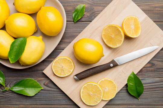 Top view with copy space for fresh and ripe lemons on cutting board. Healthy food background. Elegant background of lemon and lemon slices with squeezer and knife colored background - Powered by Adobe