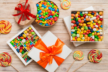 Set of different sweet candy in a paper box with a satin ribbon on a colored background. Holiday concept