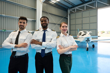 Confident student pilots posing with arms crossed in aircraft hangar