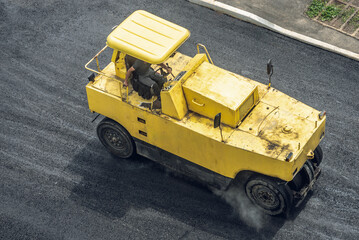 Workers lay a new asphalt coating using hot bitumen. Work of heavy machinery and paver. Top view