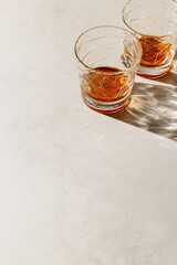 Two crystal Whiskey Glasses with shadow and sunlight reflection on beige background, minimal neutral photo, aesthetic top view summer still life, refraction at shine alcohol drink, caustics