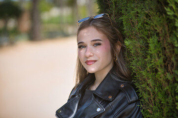 Portrait of young woman, beautiful, blonde, green eyes, with leather jacket and sunglasses, looking...