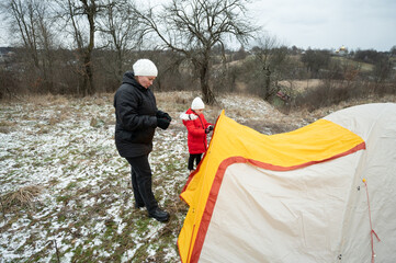 Camping adventure with family in winter landscape creating lasting memories near the fields while setting up a cozy tent in the chilly atmosphere
