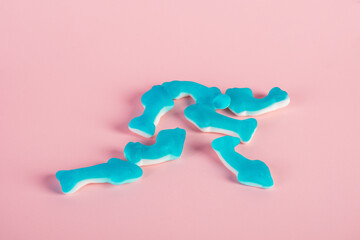 Jelly fish candies. Gummy shark, blue dolphin jelly coated with sugar on a pink background.