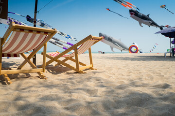 Beach seats for see the Flying kite festival with Octopus, jellyfish, fish and shaped animal. Various colorful kites flying in the blue sky . Free public event featuring local of Thailand.