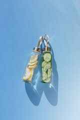 Cleansing and refreshing Lemon, cucumber water drink detox, shadow at sunlight on blue with sun...