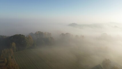 Sunrise fog over colorful autumn forest and fields