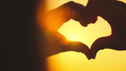 Fototapeta premium showing heart sign with hands silhouette, close-up, happy girl traveler at sunset, african american multicultural at sunset, adolescence dream, romantic love country usa, fun leisure young adult, girl