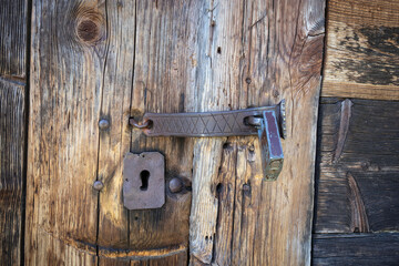 A rusty lock and key are on a wooden door