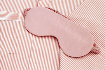 Pink eye mask for sleep on folder striped red pajama, close up texture fabric, minimal lifestyle...